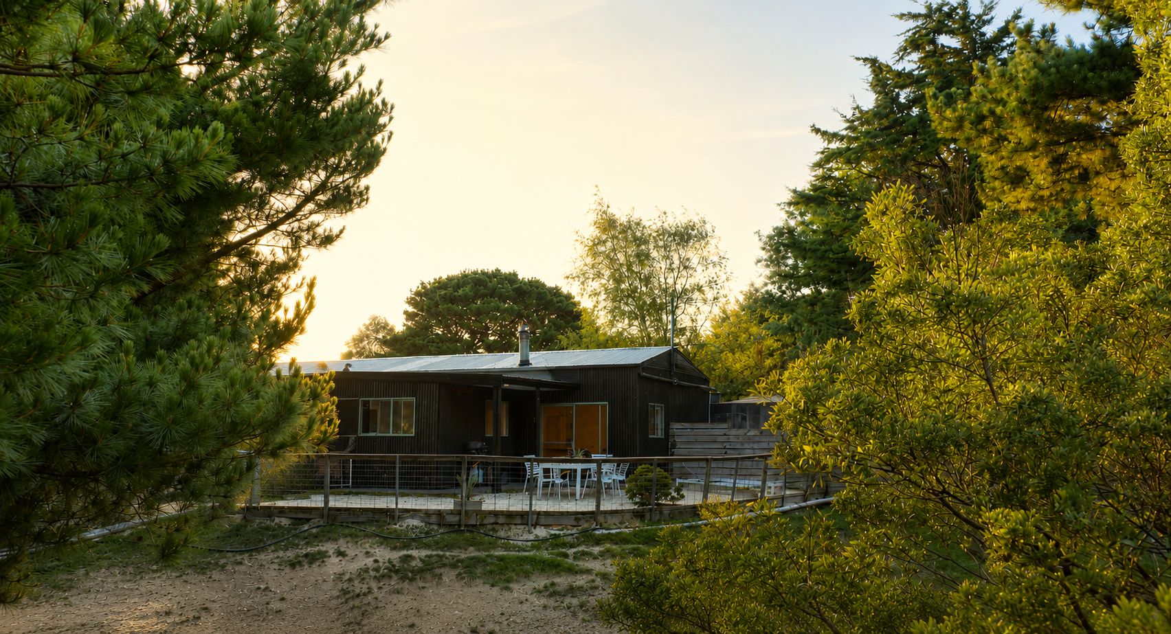 Eine Hütte mit eingezäuntem Patio, umgeben von dichtem Baumbestand.
