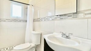 Een badkamer met toilet, wastafel en douchegordijn.