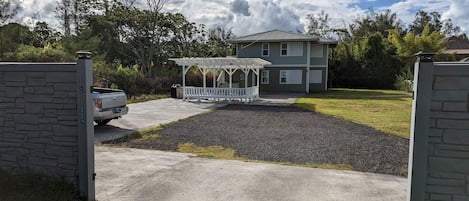 A gated driveway leading to a house with a covered porch and a well-maintained lawn.
