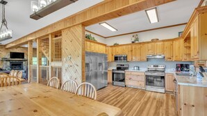A spacious kitchen with wooden cabinets, stainless steel appliances, and a dining area with a wooden table and chairs.