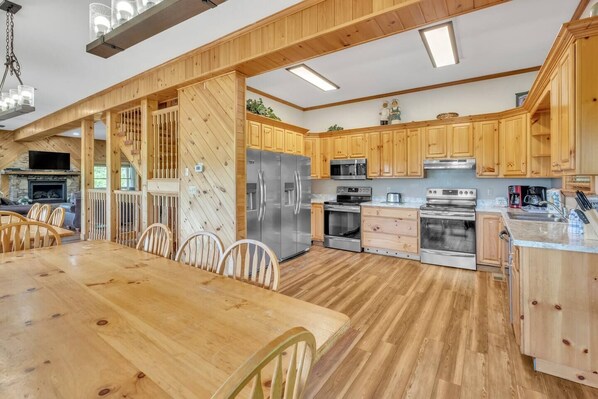 A spacious kitchen with wooden cabinets, stainless steel appliances, and a dining area with a wooden table and chairs.
