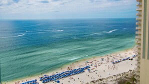 Una playa con una fila de sombrillas azules y un edificio con balcones.