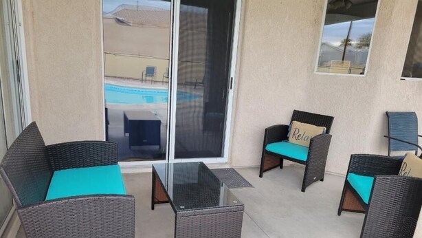 Un patio con mobiliario de mimbre y una mesa de vidrio.