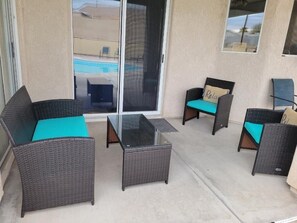 A patio area with wicker furniture and a glass table.
