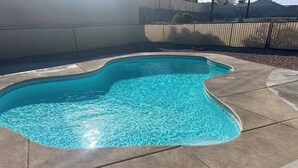 Una piscina con borde ondulado, rodeada por una terraza de hormigón.