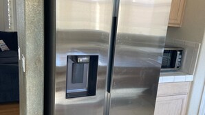 Un refrigerador Samsung de acero inoxidable en una cocina con armarios de madera y un microondas.