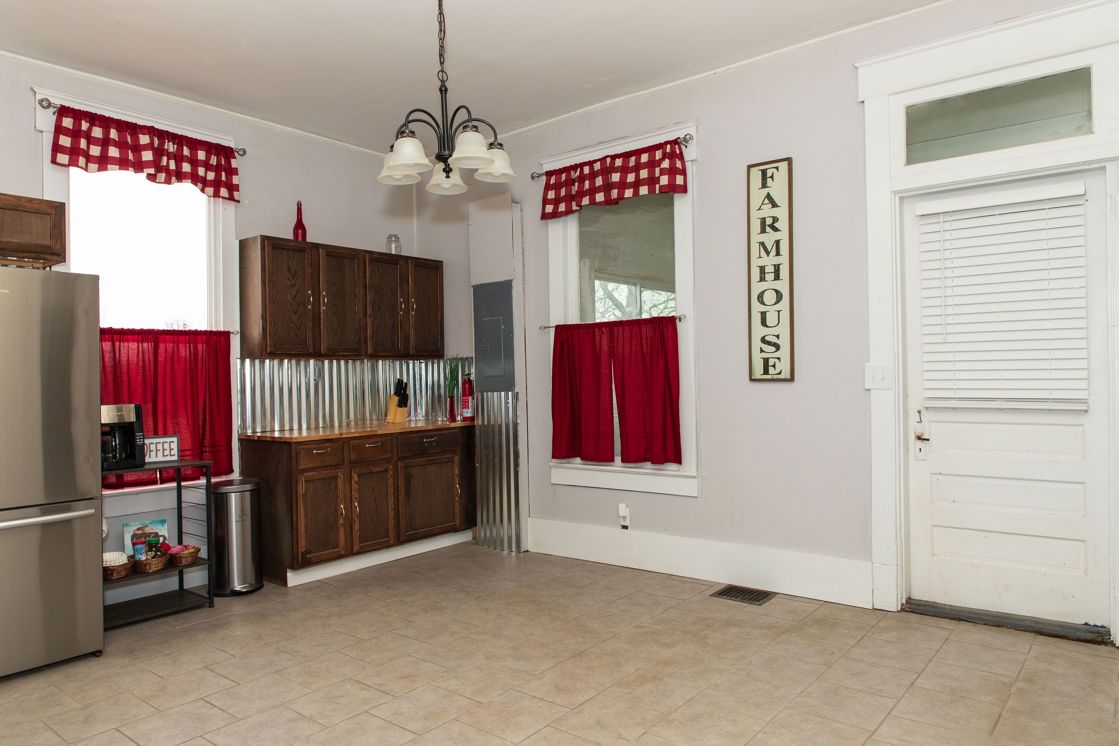A kitchen with a refrigerator, coffee maker, and a sign that reads 'FARMHOUSE.'