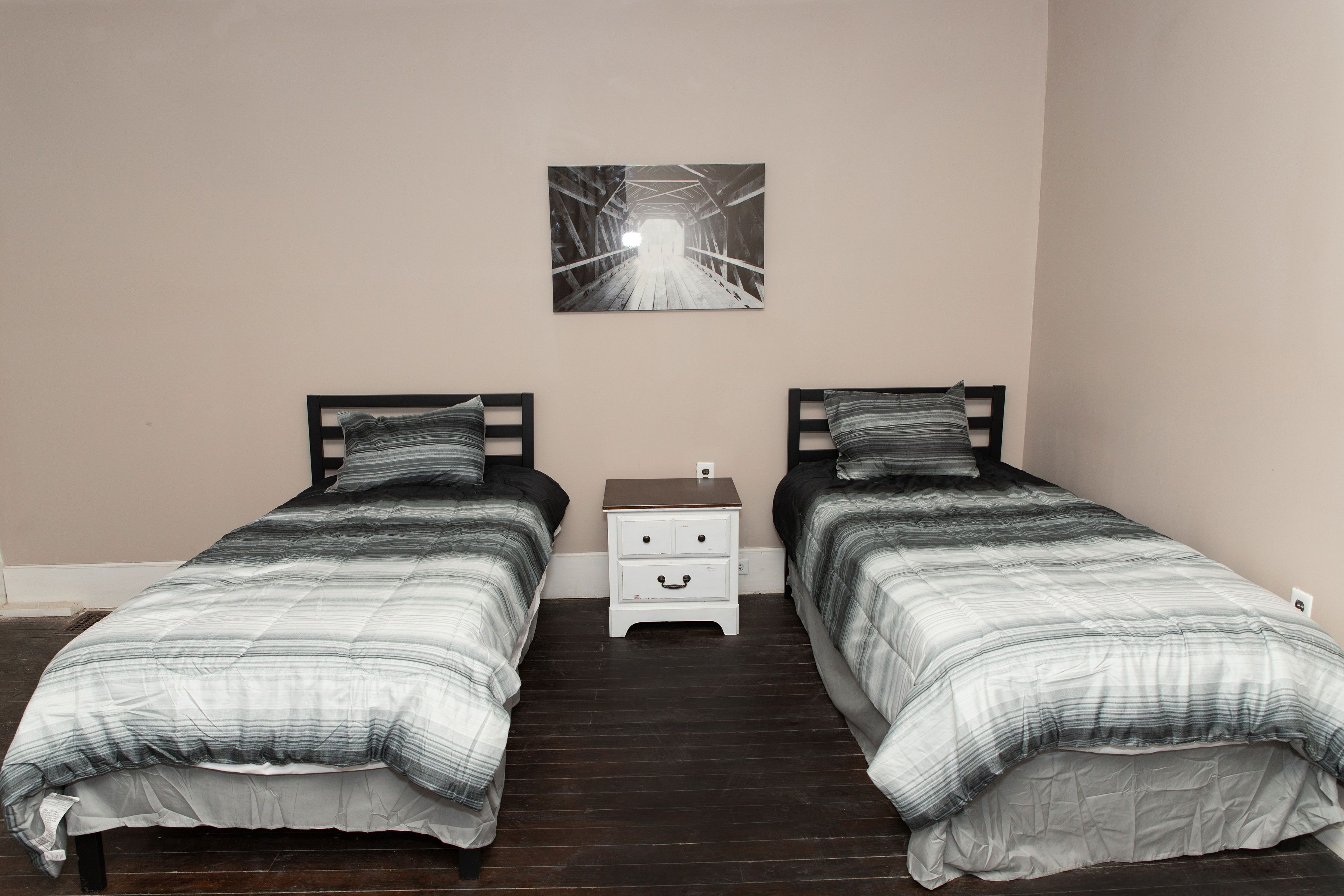 Un dormitorio con dos camas, una mesita de noche y un cuadro colgado en la pared.