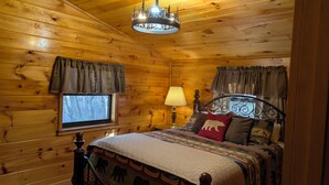 A wooden cabin bedroom with a bed, curtains, a lamp, and a chandelier. - ROD RUN! Breathtaking View,Hot Tub, Pet Friendly,9.8🌟 Rated










 (Sevierville)