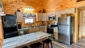 A compact kitchen with wooden walls, a marble countertop, and basic appliances including a refrigerator, microwave, and stove. - ROD RUN! Breathtaking View,Hot Tub, Pet Friendly,9.8🌟 Rated










 (Sevierville)