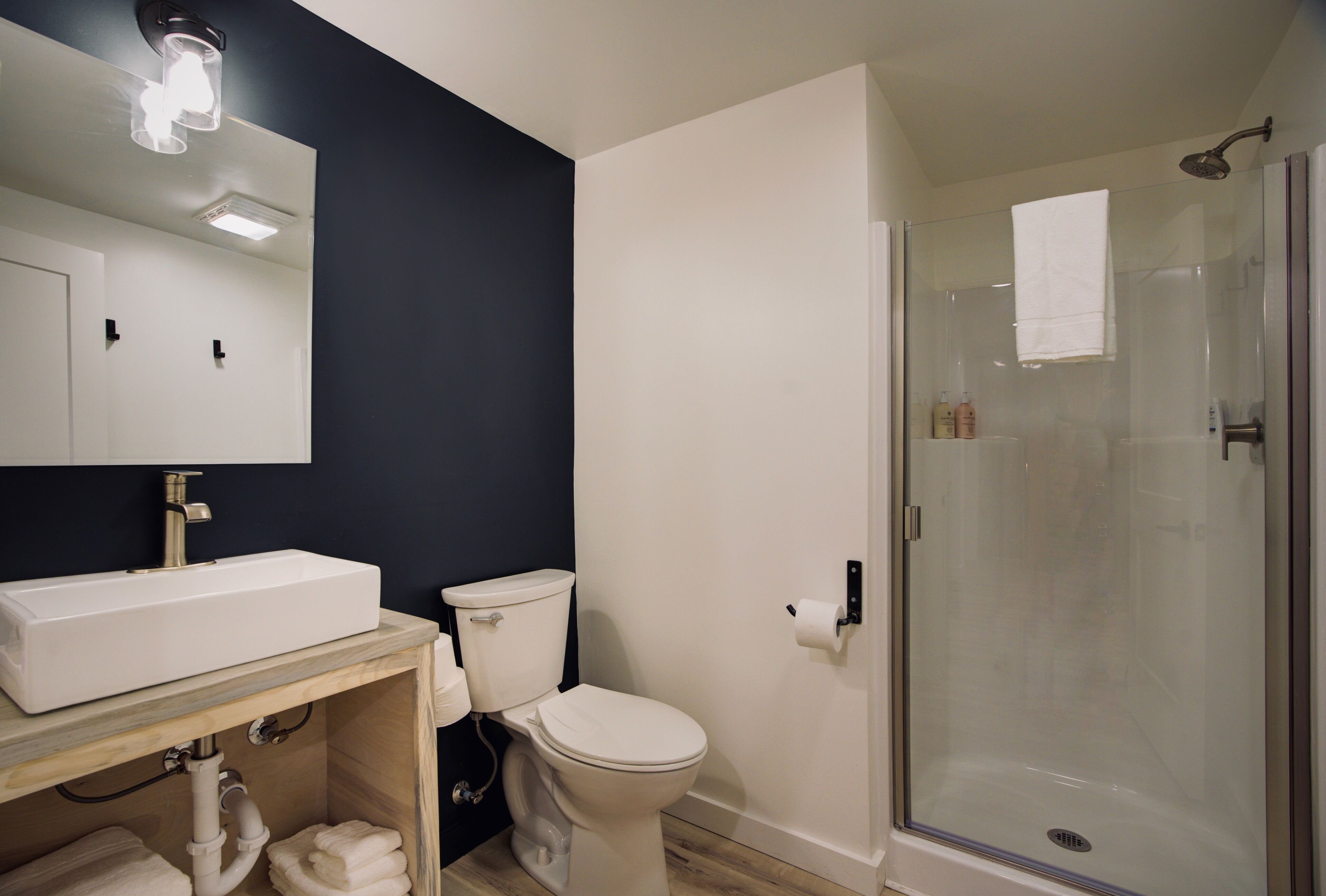 Une salle de bain moderne avec un lavabo blanc, des toilettes et une douche à parois de verre.