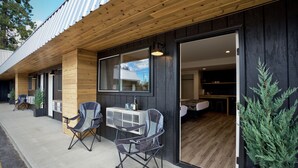 Un edificio moderno con fachada de madera y grandes puertas correderas de vidrio que dan a una habitación con suelo de madera y una cama.