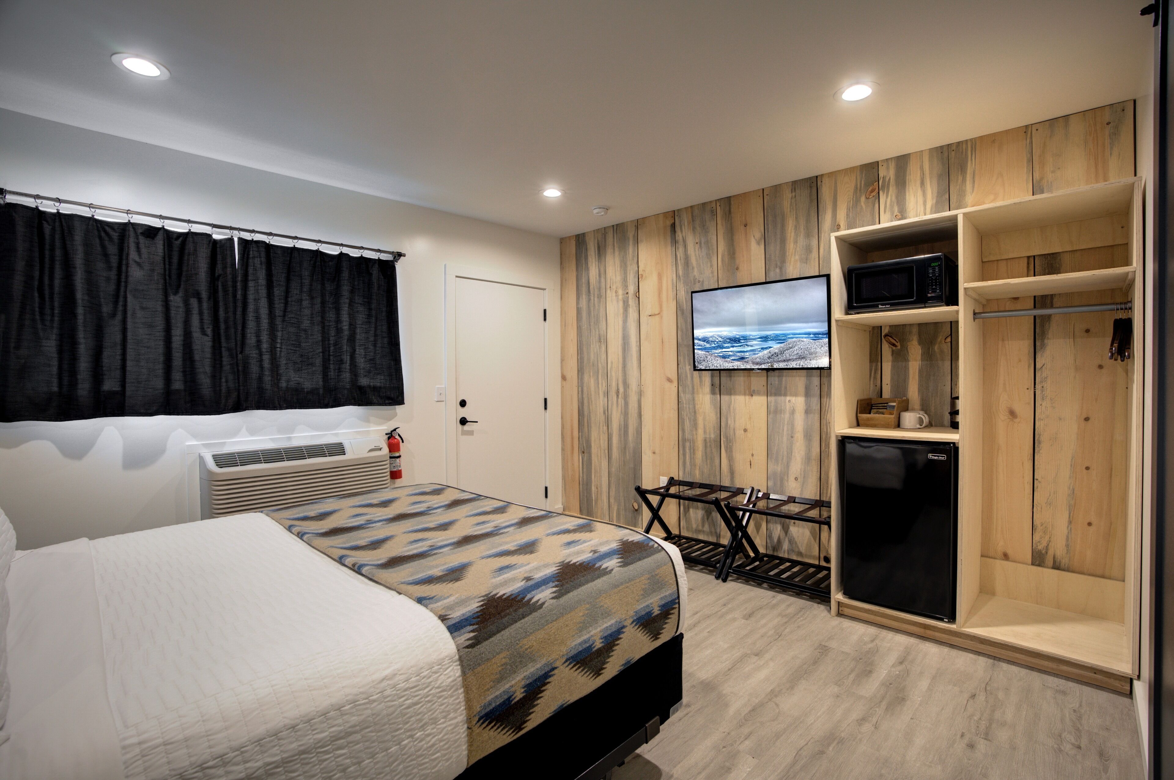 Une chambre d’hôtel équipée d’un lit, d’un bureau, d’une télévision, d’un four à micro-ondes et d’une armoire.