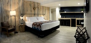 A modern hotel room with a large bed, a wooden accent wall, a desk, and a chair.