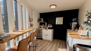 Una cocina moderna con encimeras de madera, microondas y fregadero. Hay tres sillas y una mesa de comedor.