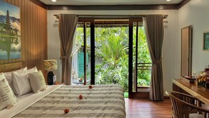 A bedroom with a bed, a desk, and a view of greenery through a large window. - The Palms Canggu (Canggu)