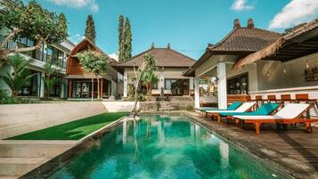 Una piscina al aire libre, sillones reclinables de piscina