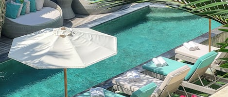 Una piscina al aire libre, sillones reclinables de piscina