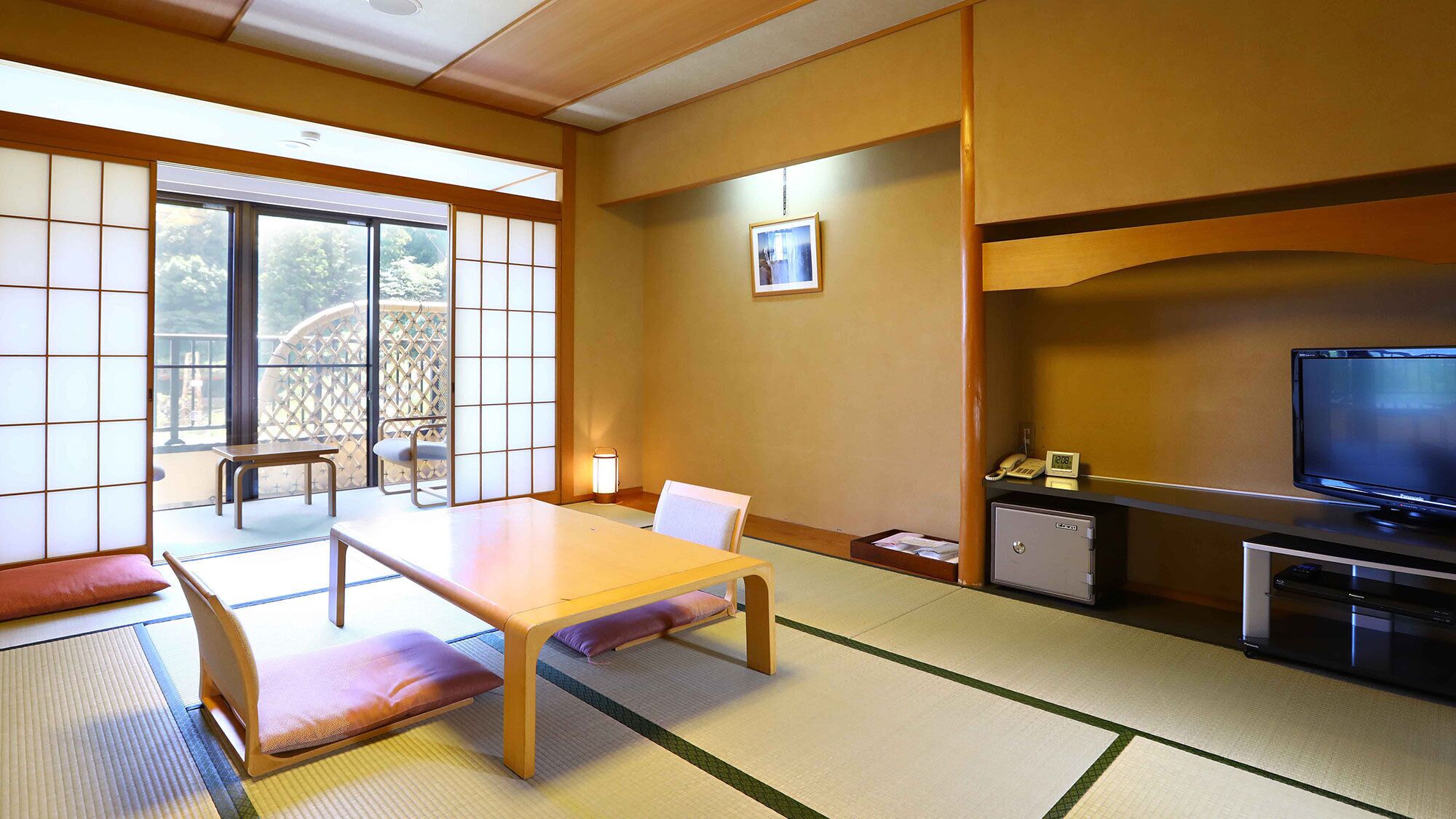 A traditional Japanese room with tatami flooring, a low table, and a television.