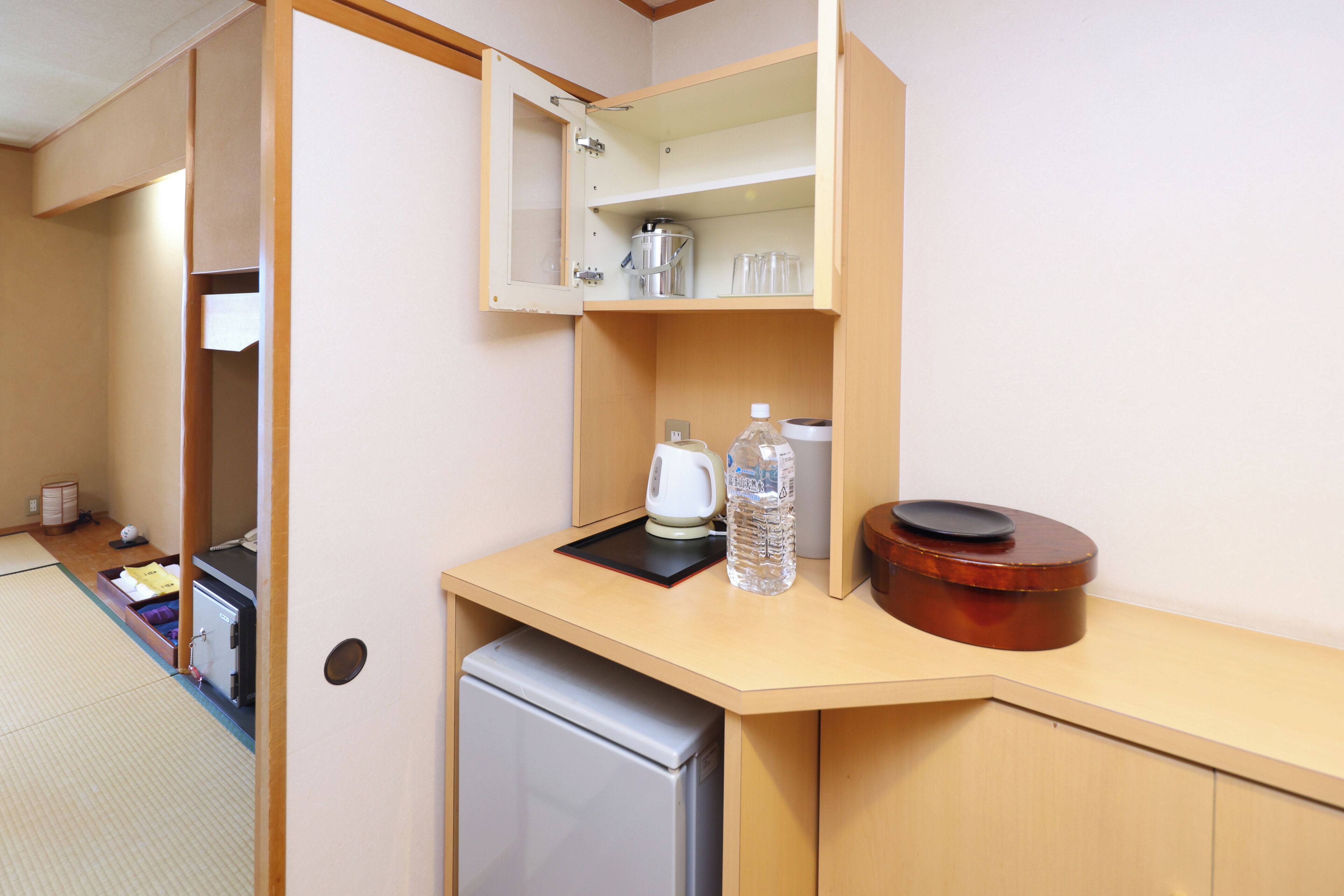 A compact kitchen with a refrigerator, a microwave, a kettle, and a coffee maker.