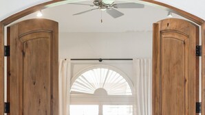 Ein Schlafzimmer mit einem Bett, einem Deckenventilator und einem Fenster mit Vorhängen.