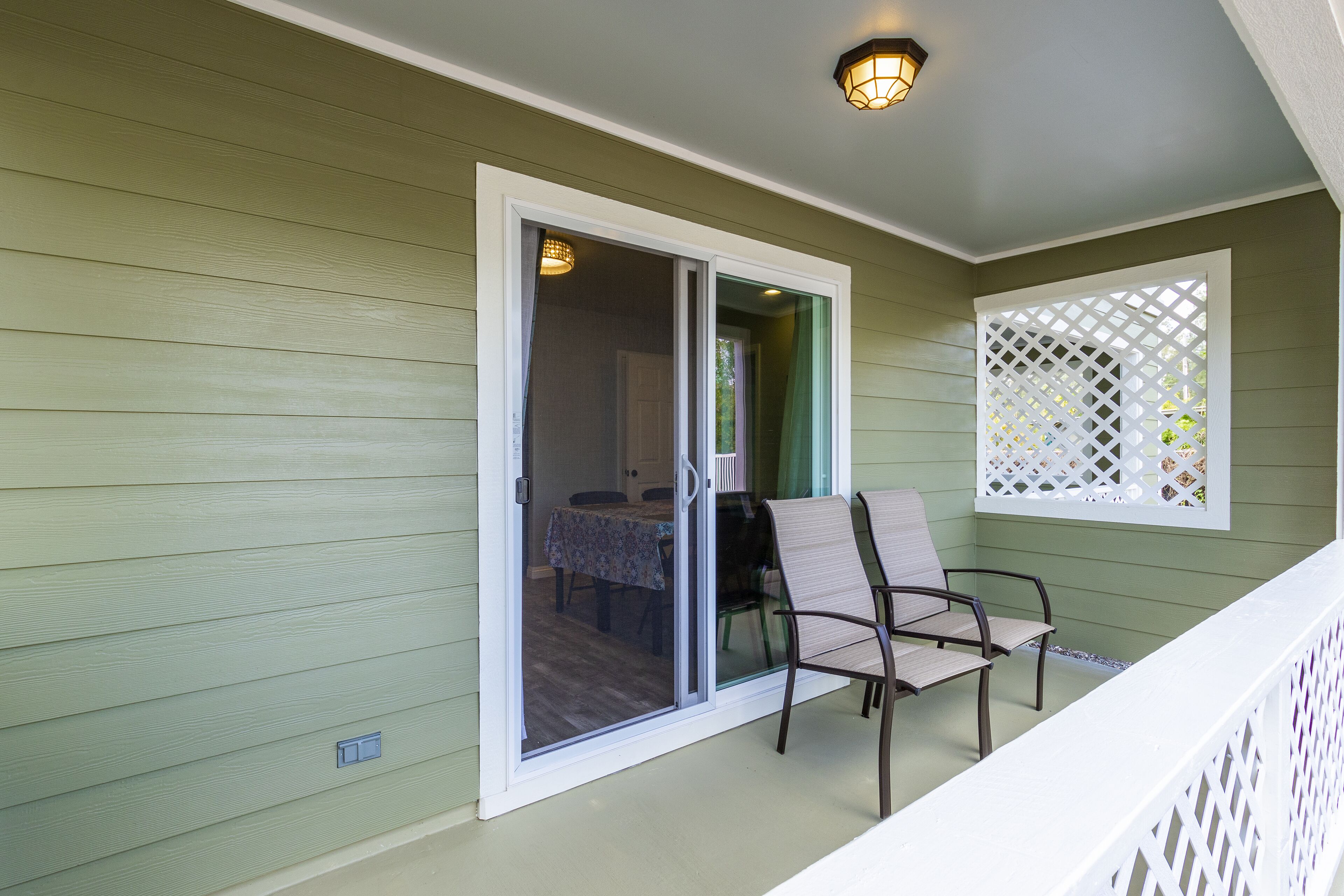 A balcony with a table and chairs, a sliding glass door, and a white lattice screen.
