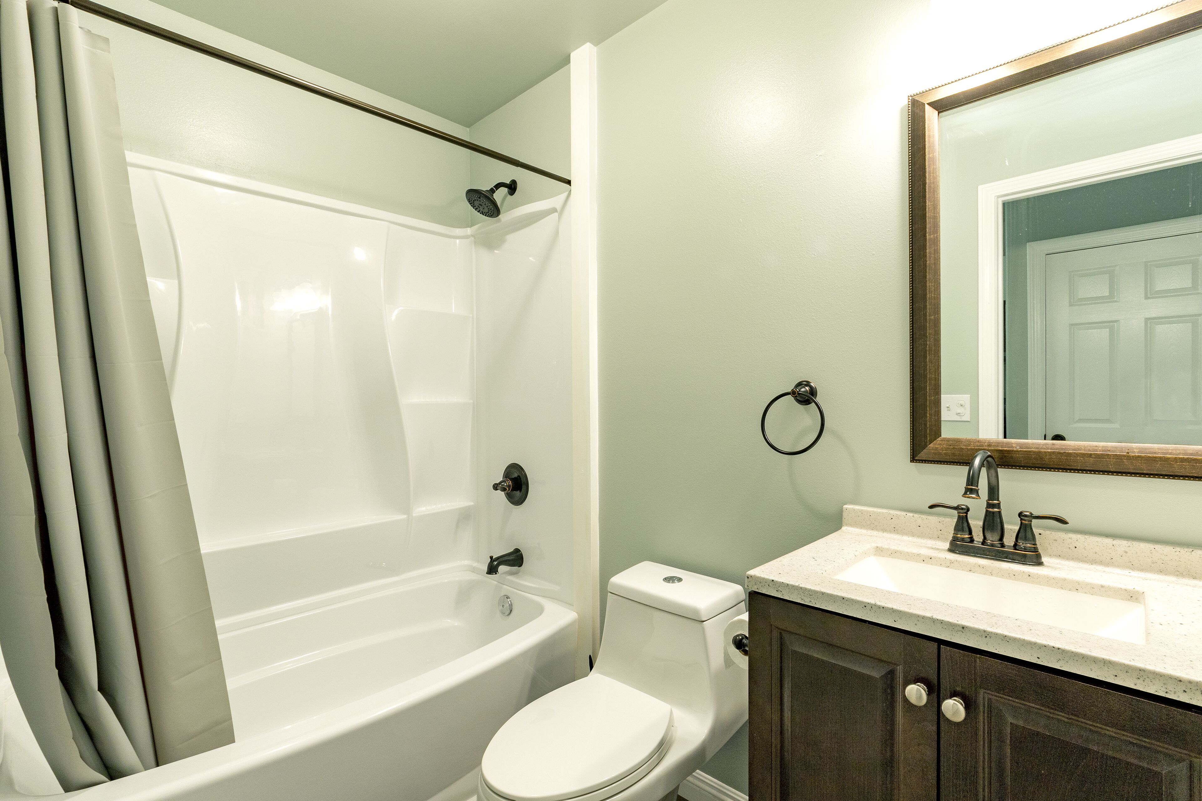 A bathroom with a bathtub, toilet, sink, and mirror.