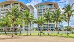 A hotel with two white buildings, multiple balconies, and palm trees in the foreground. - Diamante sol 502S Dual Master Steps min walk 2 town (Jaco)