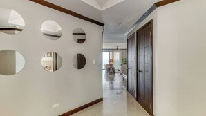 A hallway with a series of circular mirrors on the wall, a wooden trim, and a door at the end. - Diamante sol 502S Dual Master Steps min walk 2 town (Jaco)