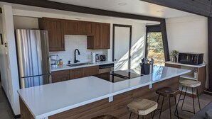Une cuisine moderne dotée d’un grand îlot central, de meubles en bois, d’appareils électroménagers en acier inoxydable et de tabourets de bar.