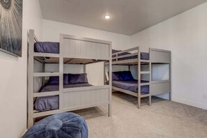A room with bunk beds, a single chair, and a painting on the wall.