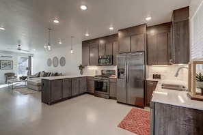 A modern kitchen with dark cabinetry, stainless steel appliances, and a central island.