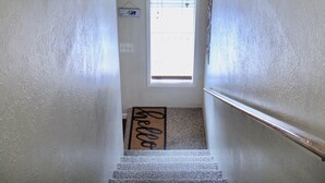 Una escalera con un ventilador de techo, un ventanal y una planta en maceta.