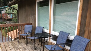 Una terraza de madera con cuatro sillas azules y una pequeña mesa redonda.