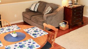 Una sala acogedora con una mesa de comedor de madera, sillas, un sofá y un mueble bajo.