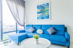 A modern living room with a blue sofa, a white coffee table, and a city view through large windows.