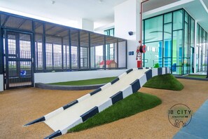 A children's play area with a slide and artificial grass.