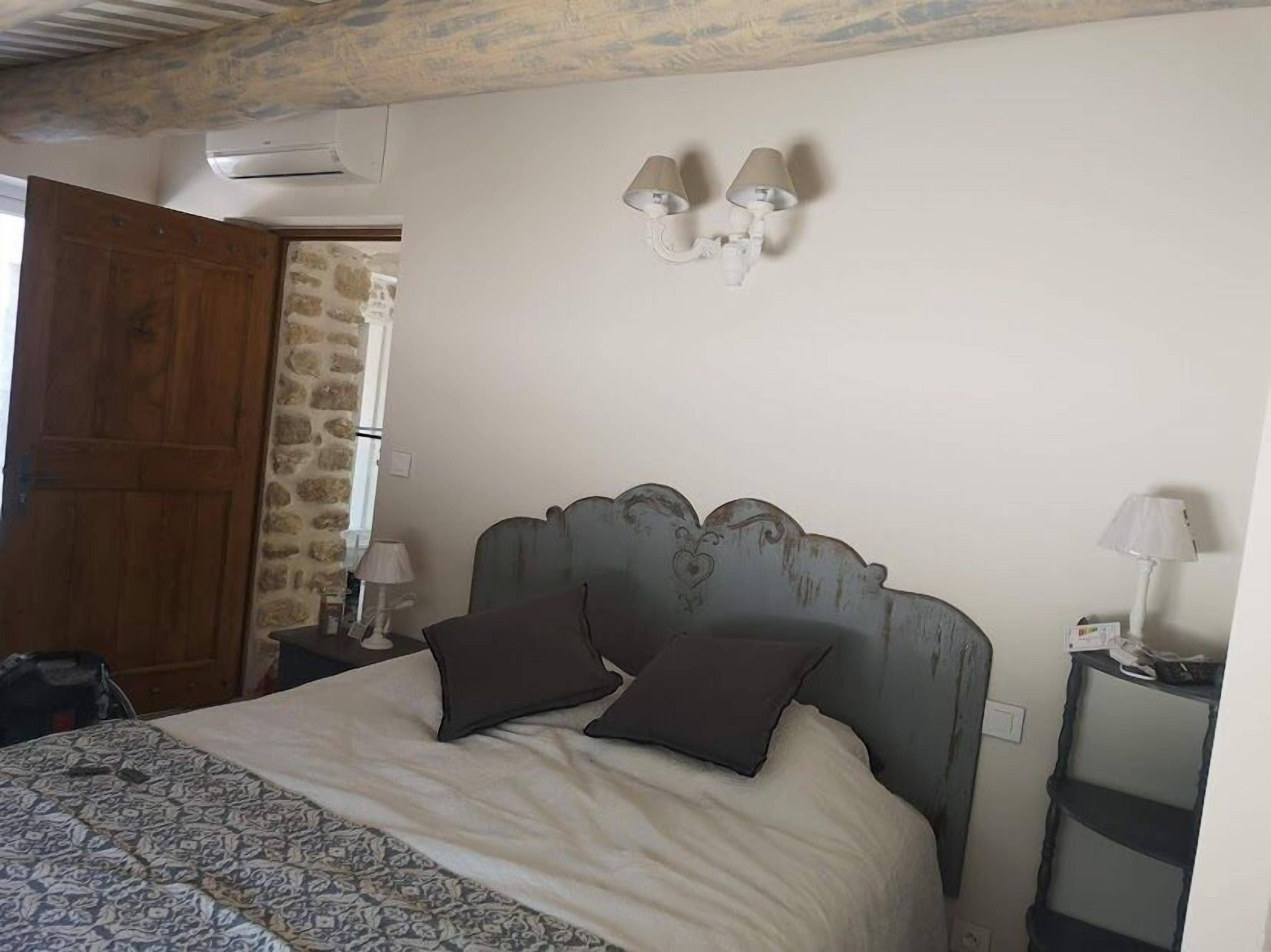 Een slaapkamer met een bed, twee bedlampen, een stenen muur en een houten deur.