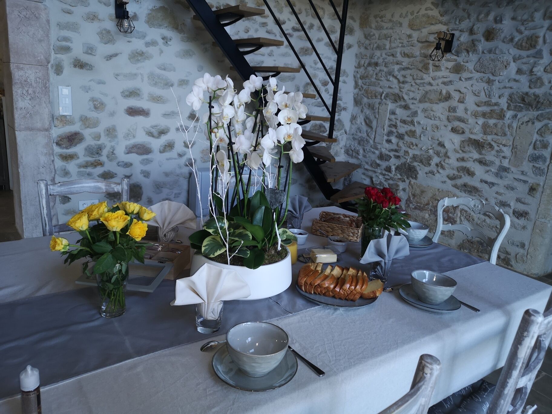A dining table set with flowers, bread, and a candle.