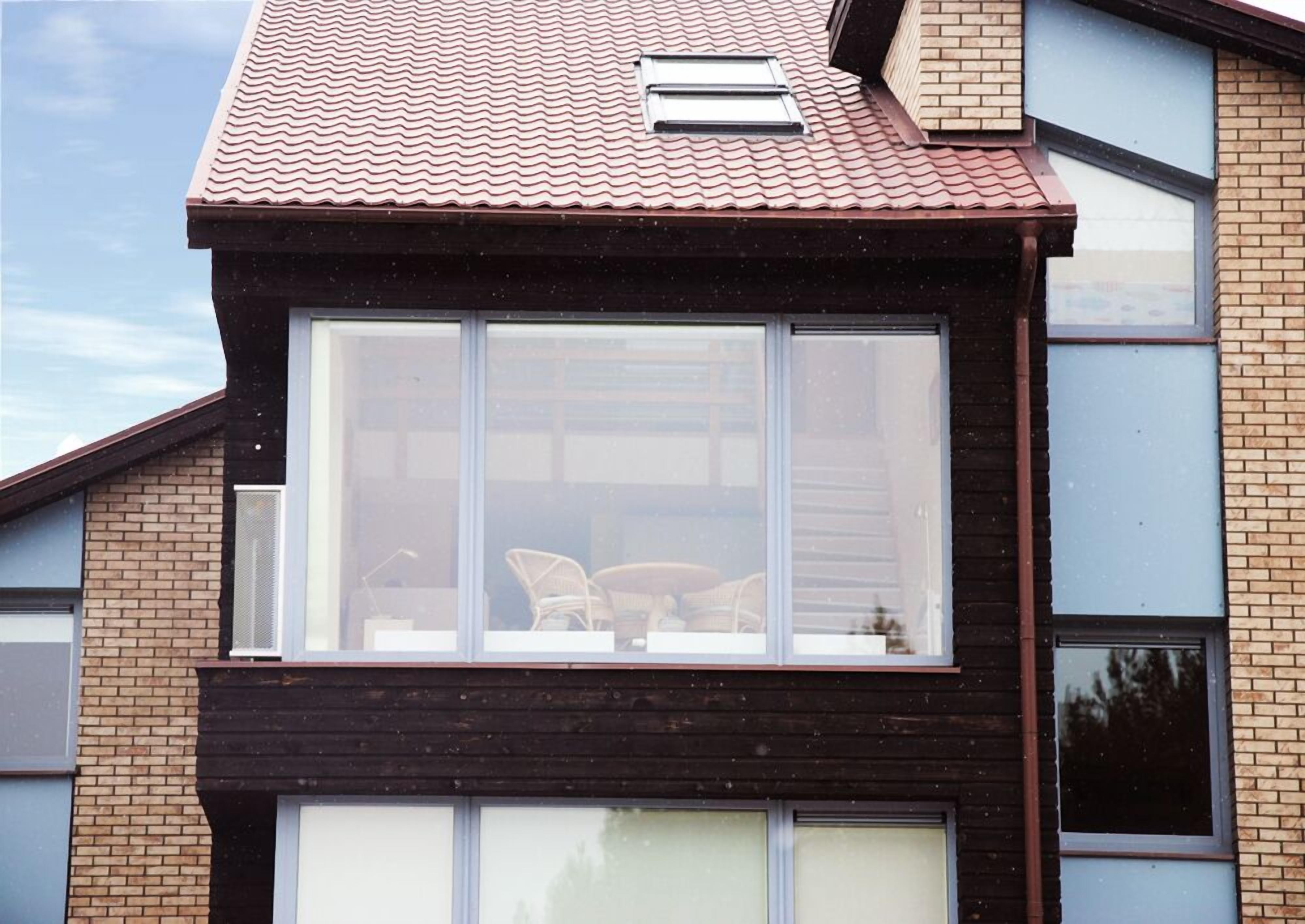 Een modern huis met een groot raam, bakstenen muren en een pannendak.