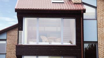 Een modern huis met een groot raam, bakstenen muren en een pannendak.