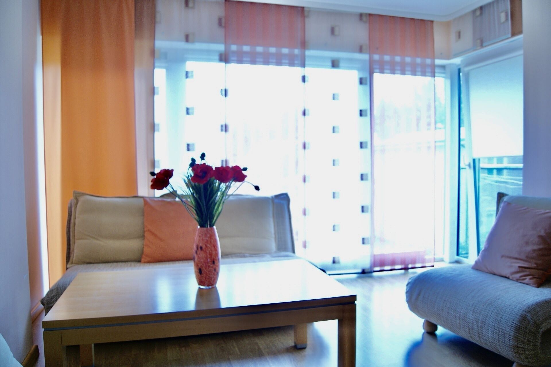 A modern living room with a sofa, a coffee table, and a vase with flowers.