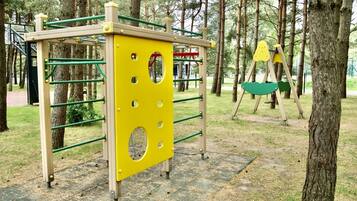 Un parque infantil con una estructura amarilla para escalar y columpios.