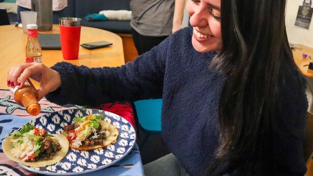 A person sitting at a table with a plate of food, a bottle, and a red cup.