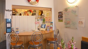 A reception area with a wooden counter, metal chairs, a life preserver sign, a whiteboard with various notices, and a computer monitor.
