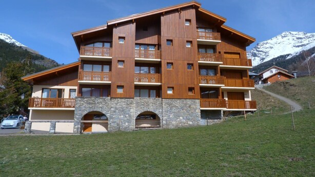 A multi-story hotel with balconies, stone arches, and a mountainous backdrop. - Superb 2 room apartment (1 bedroom) + mezzanine ...... at the foot of the slopes! (Lanslevillard)