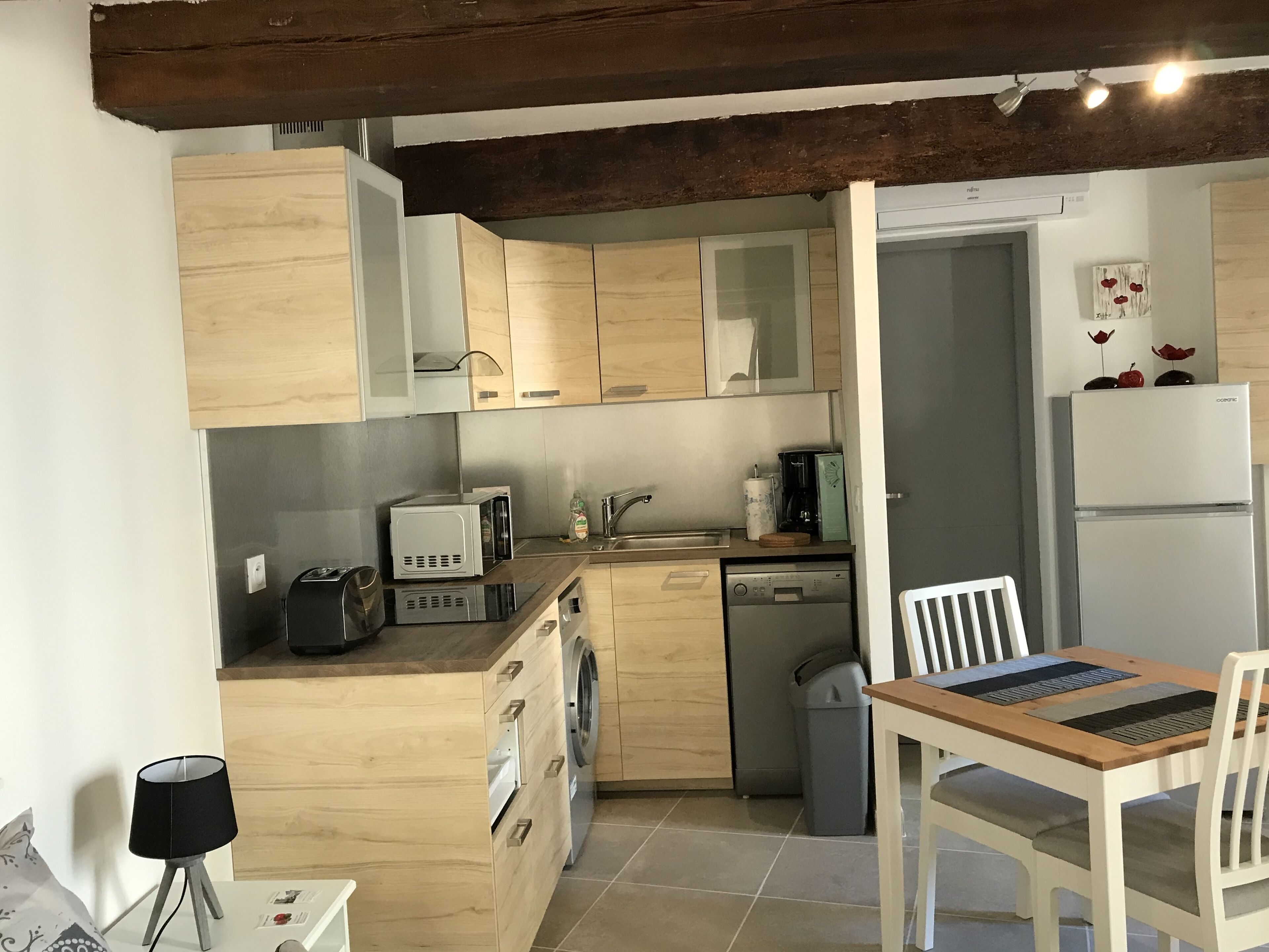 Une cuisine compacte dotée de meubles en bois, d’un lave-vaisselle encastré, d’une machine à café et d’un réfrigérateur.