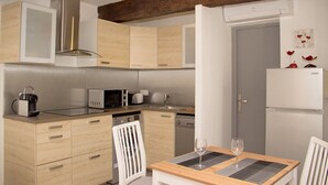 A modern kitchen with wooden cabinets, a microwave, a coffee maker, and a dining area with a table and chairs.