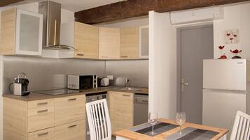 Une cuisine moderne dotée de meubles en bois, d’un four à micro-ondes, d’une machine à café et d’un coin repas avec une table et des chaises.