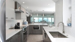 Cocina moderna con electrodomésticos de acero inoxidable, una isla grande con fregadero y vistas al área de estar.